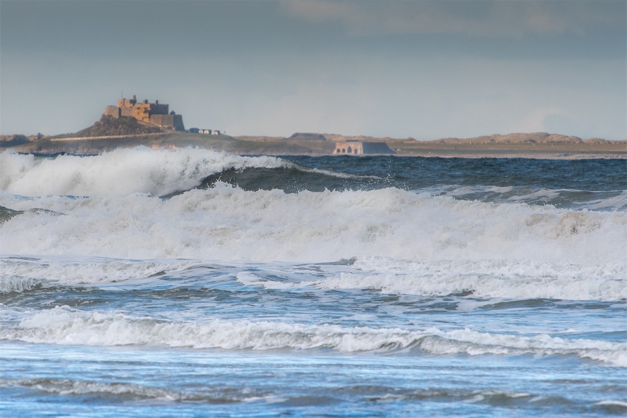 Lindisfarne Castle and Holy Island over the crashing waves of Budle Bay